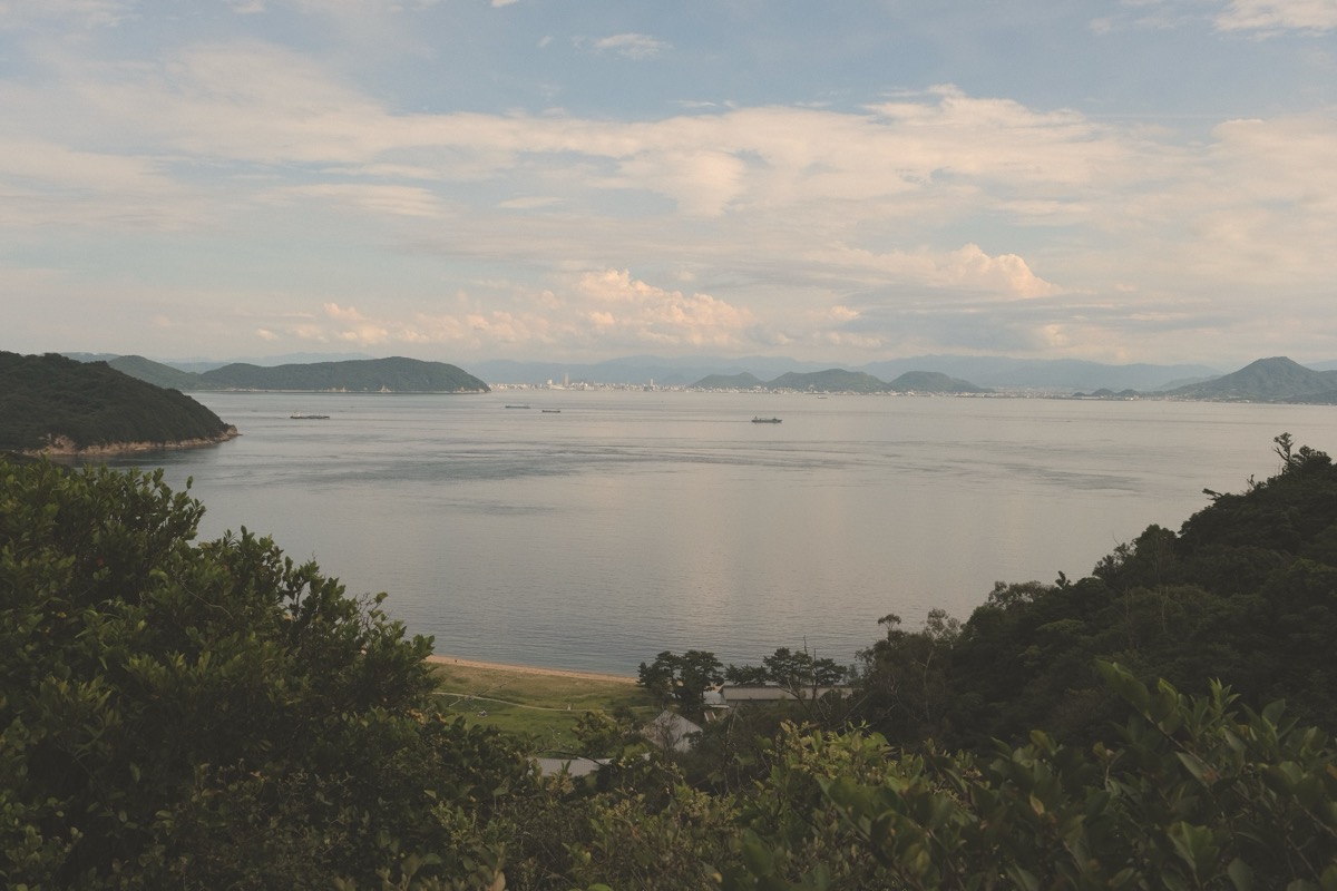 View across the Seto Inland Sea from Naoshima, with wooded headlands framing open water and a distant shoreline